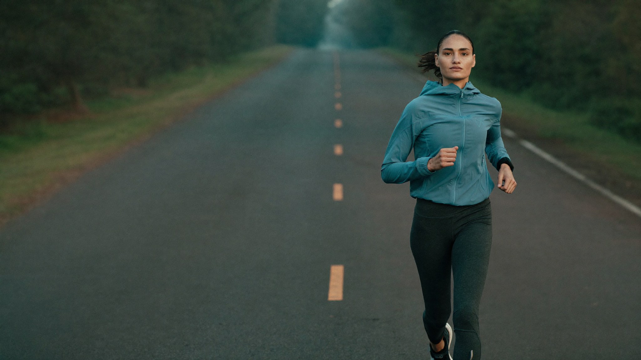 Woman running device-free on an open road. WE-STIM fabric, nothing to carry